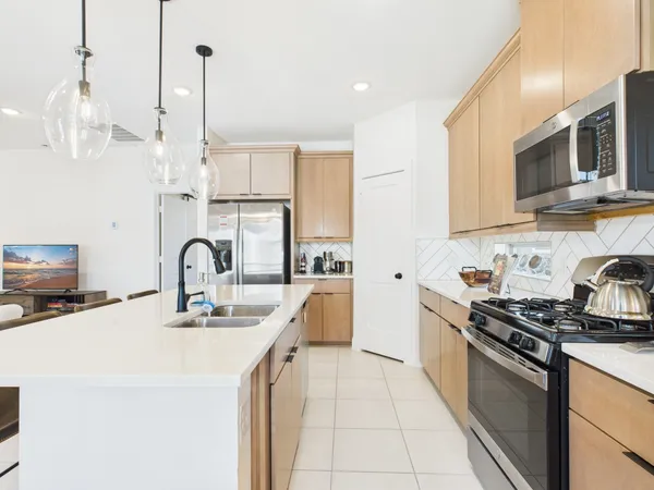 a kitchen with stainless steel appliances a sink a stove a microwave and wooden floor
