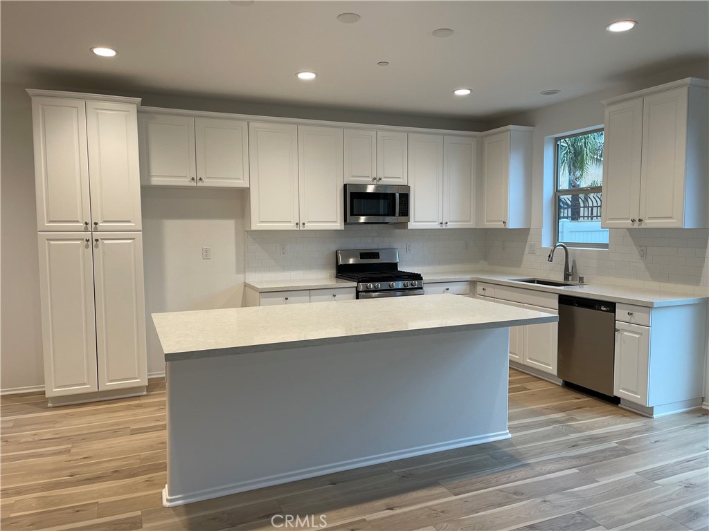 349 Lilly Street Rialto, CA 92376 - Photo 3 of 25 a kitchen with kitchen island granite countertop a sink cabinets and wooden floor