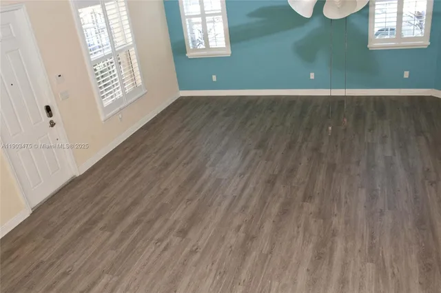 an empty room with wooden floor and windows