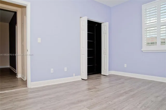 an empty room with wooden floor and a cabinet
