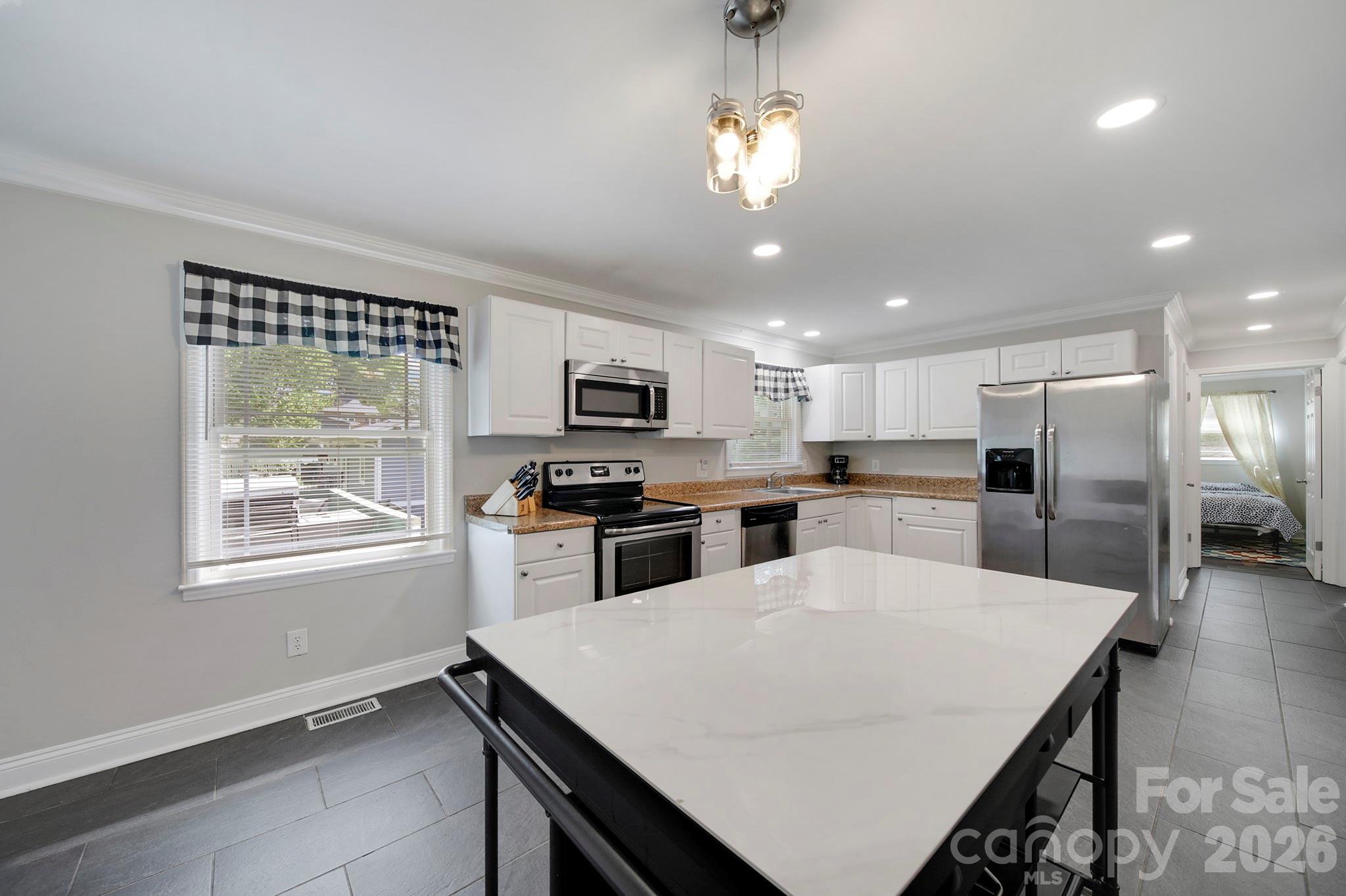 100 Privette Street Fort Mill, SC 29715 - Photo 8 of 25 a kitchen with stainless steel appliances kitchen island granite countertop a refrigerator a stove top oven a sink dishwasher and white cabinets with wooden floor