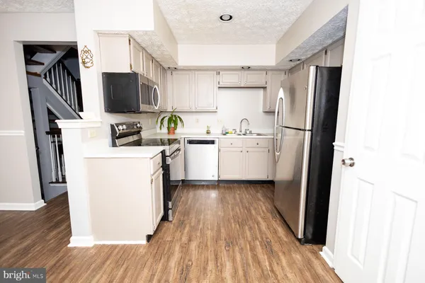 a kitchen with a sink a refrigerator a stove top oven and wooden floor