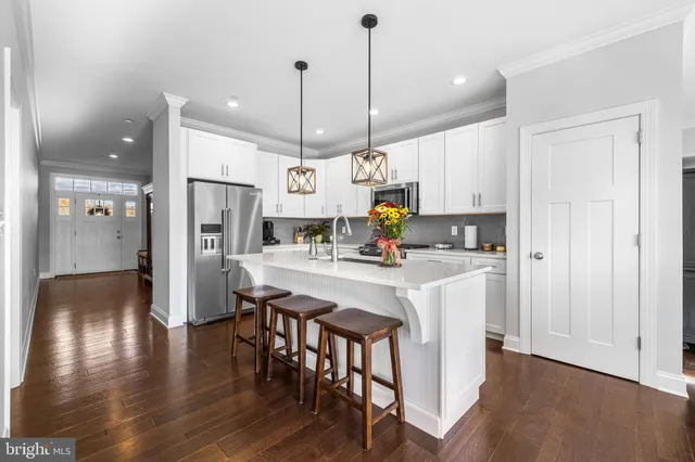 a kitchen with stainless steel appliances a refrigerator a stove a sink dishwasher and white cabinets with wooden floor