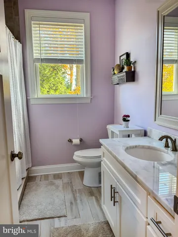 a bathroom with a granite countertop sink toilet and a window