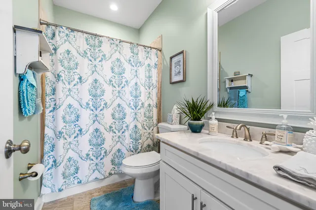 a bathroom with a granite countertop sink a toilet and a mirror