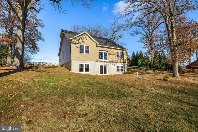 a view of a white house next to a yard with large trees