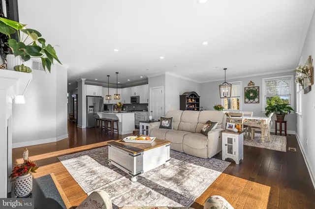 a living room with furniture a rug kitchen view and a table