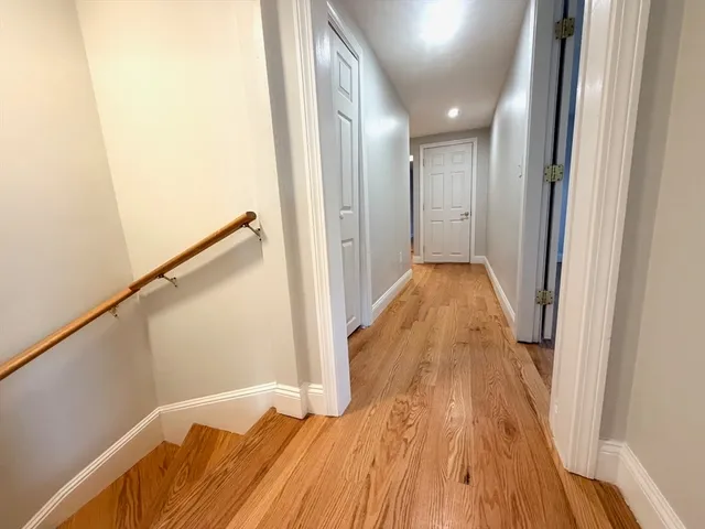 a view of a hallway with wooden floor and staircase
