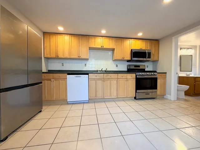 a kitchen with stainless steel appliances granite countertop a stove a sink and a refrigerator