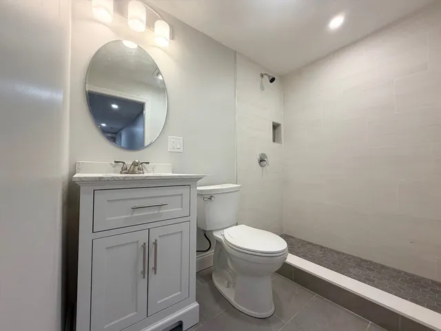 a bathroom with a toilet sink vanity and mirror