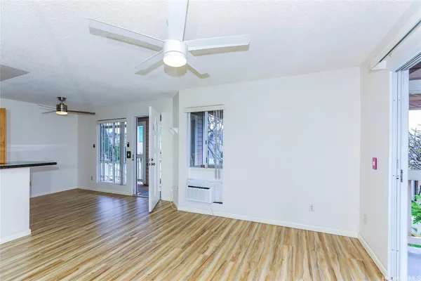 a view of an empty room with wooden floor and a window