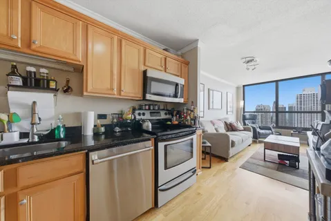 a kitchen with stainless steel appliances granite countertop a stove a sink dishwasher and white cabinets with wooden floor