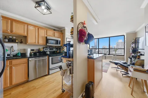 a kitchen with stainless steel appliances granite countertop a refrigerator a stove top oven a sink dishwasher and white cabinets with wooden floor