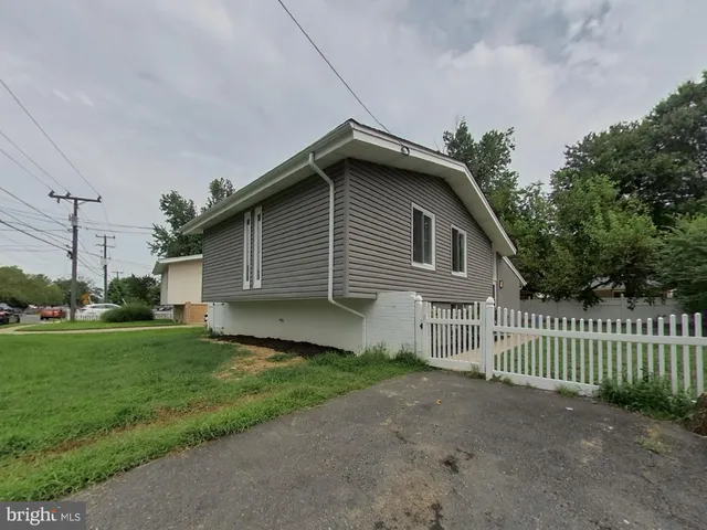 a view of a house with a yard plants and large tree