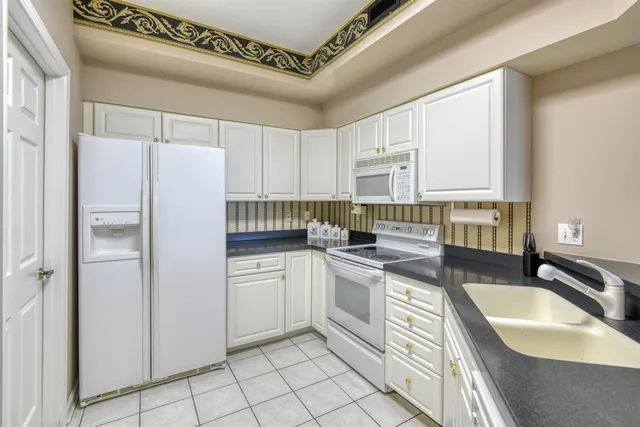 a kitchen with granite countertop a sink a counter top space stainless steel appliances and cabinets