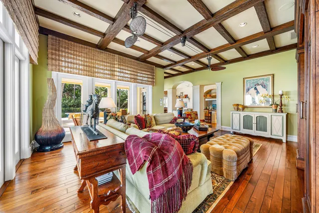 a living room with furniture a large window and wooden floor