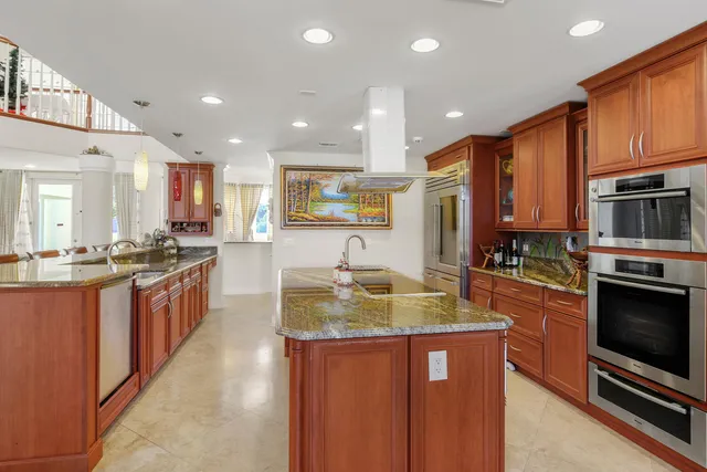 a large kitchen with stainless steel appliances granite countertop a stove top oven a sink dishwasher a dining table and chairs