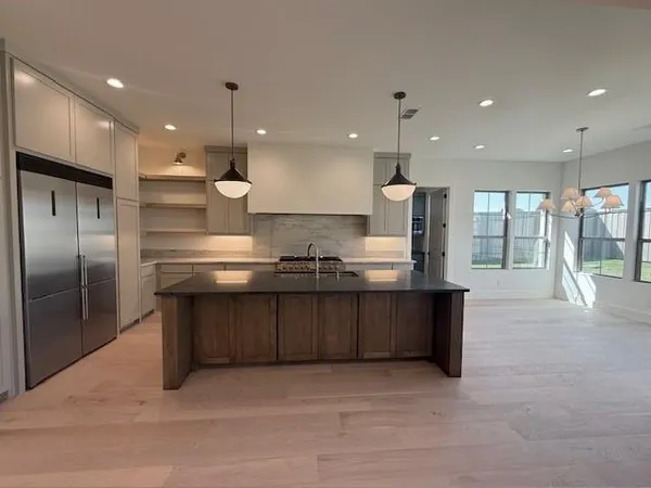 a large kitchen with stainless steel appliances kitchen island granite countertop a large counter top and a stove top oven