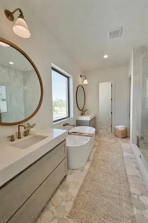 a bathroom with a double vanity sink mirror and bathtub