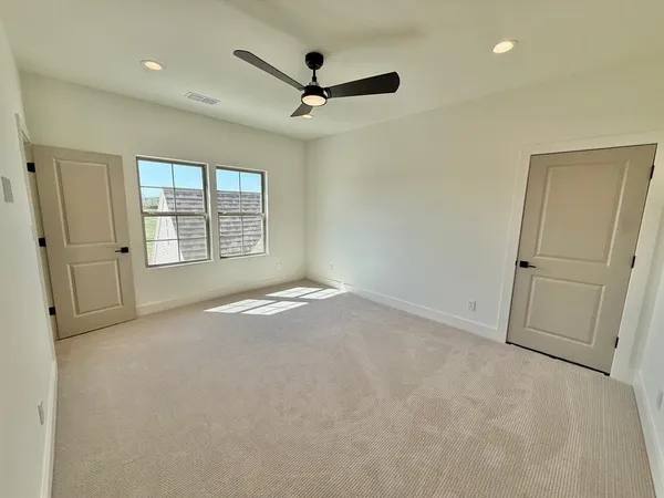 an empty room with windows and ceiling fan