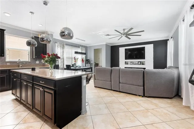 a large living room with stainless steel appliances kitchen island granite countertop a sink a counter top space and a view of living room