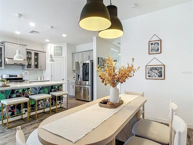 a living room with stainless steel appliances furniture a chandelier and a dining table