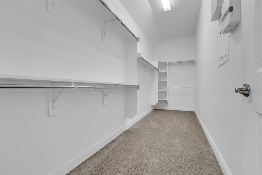 1011 Prairie Ridge Lane Arlington, TX 76005 - Photo 31 of 32 Walk-in closet featuring built-in shelving, hanging rods, and neutral-toned carpet flooring