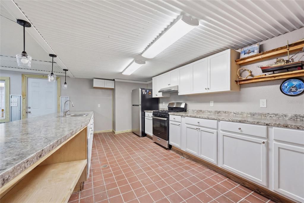 505 3rd Street Cedar Key, FL 32625 - Photo 11 of 37 a kitchen with granite countertop a sink stove and cabinets