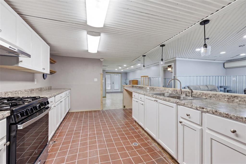 505 3rd Street Cedar Key, FL 32625 - Photo 15 of 37 a kitchen with granite countertop lots of white cabinets a sink and stainless steel appliances