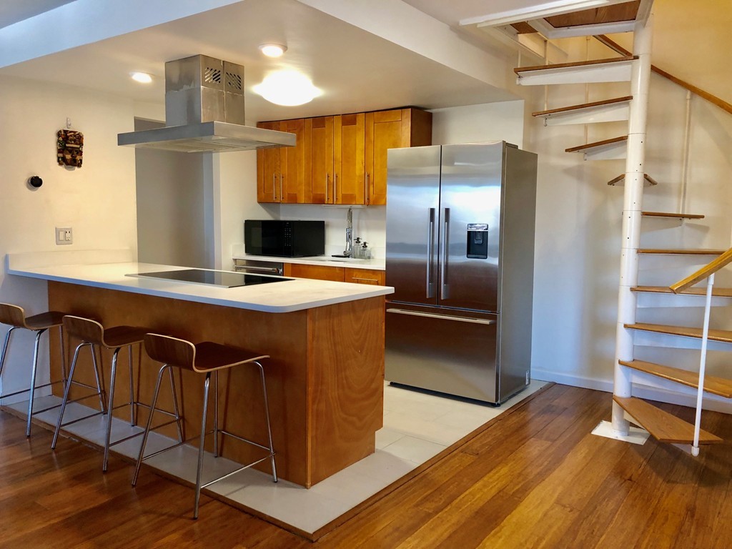 a kitchen with kitchen island a stove a refrigerator and wooden floor