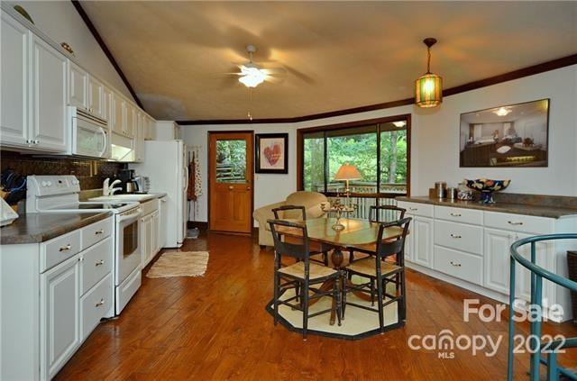 55 Summit Road Tryon, NC 28782 - Photo 12 of 23 a kitchen with stainless steel appliances kitchen island granite countertop a stove a sink a dining table and chairs with wooden floor