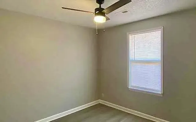 an empty room with a window and ceiling fan
