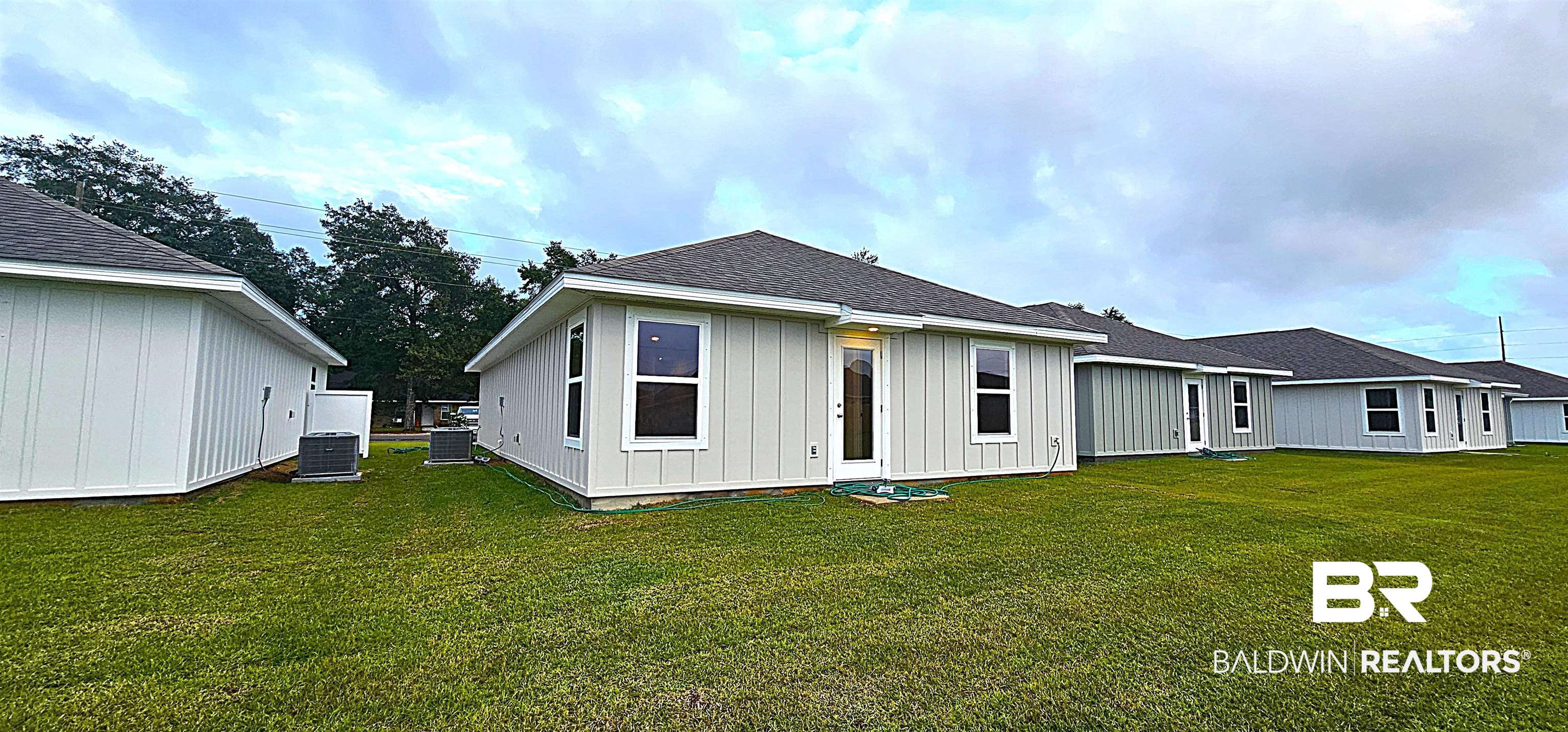 1060 South Bay Street Foley, AL 36535 - Photo 9 of 35 Rear view of house with central air condition unit and a lawn