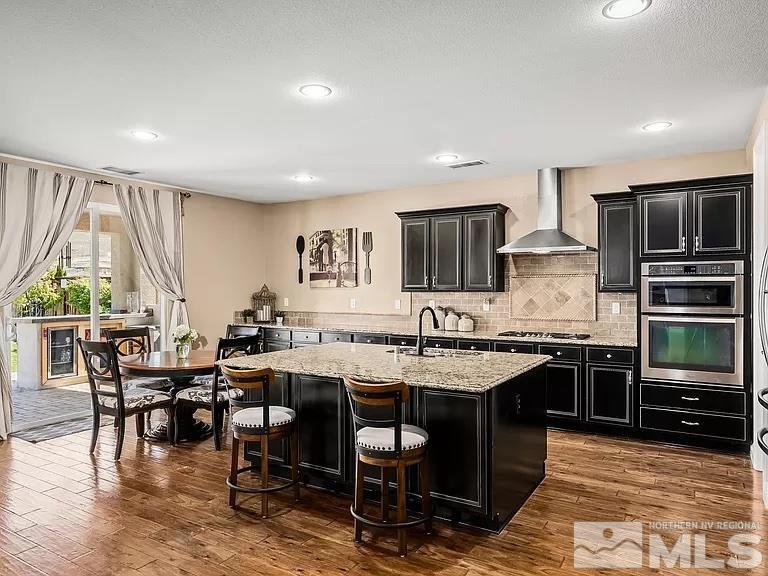 2725 Foxhunter Lane Reno, NV 89521 - Photo 7 of 25 a open kitchen with stainless steel appliances granite countertop a stove top oven a sink dishwasher a dining table and chairs with wooden floor