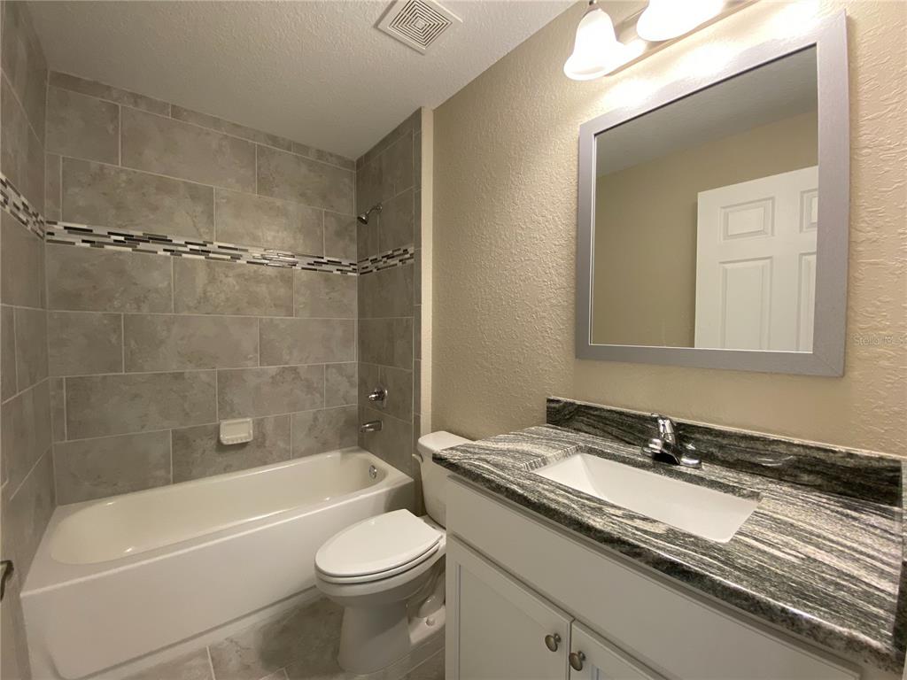 3011 Southwest 140th Loop Ocala, FL 34473 - Photo 12 of 22 a bathroom with a granite countertop sink a toilet and bathtub