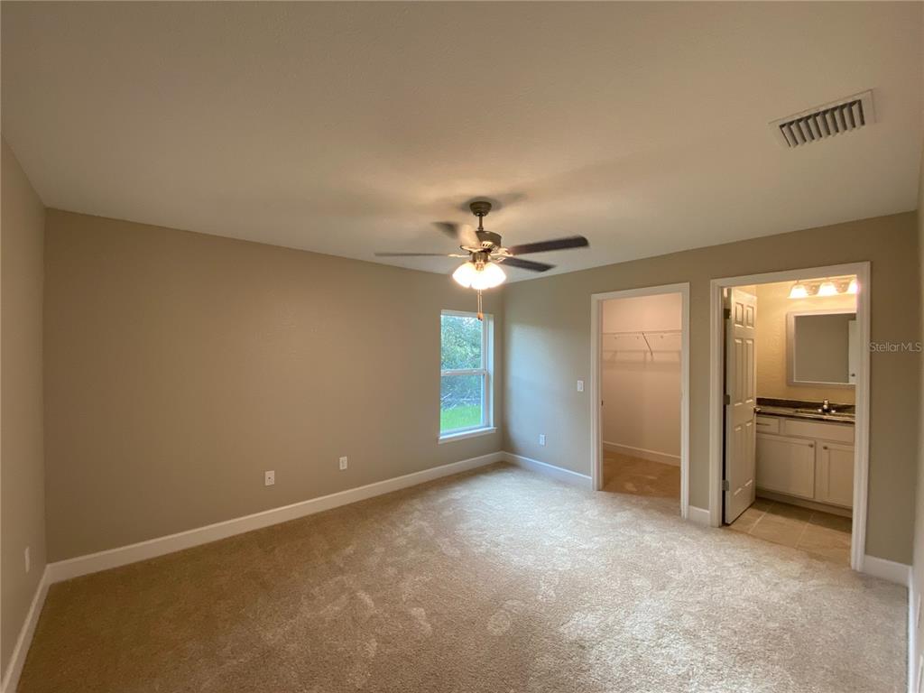 3011 Southwest 140th Loop Ocala, FL 34473 - Photo 13 of 22 an empty room with chandelier fan and windows