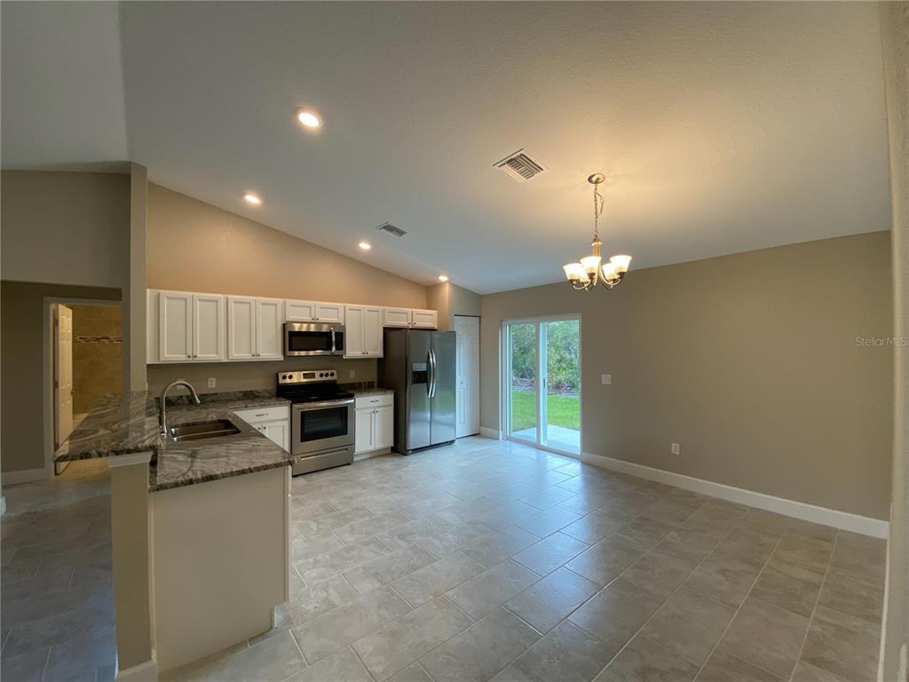3011 Southwest 140th Loop Ocala, FL 34473 - Photo 5 of 22 a kitchen with kitchen island granite countertop a stove and a sink
