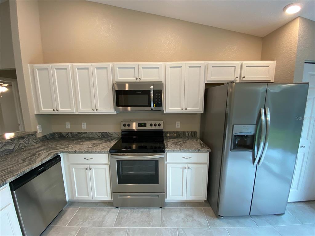 3011 Southwest 140th Loop Ocala, FL 34473 - Photo 7 of 22 a kitchen with stainless steel appliances wooden cabinets a stove a microwave and a refrigerator