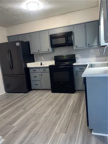a kitchen with granite countertop a refrigerator stove and sink