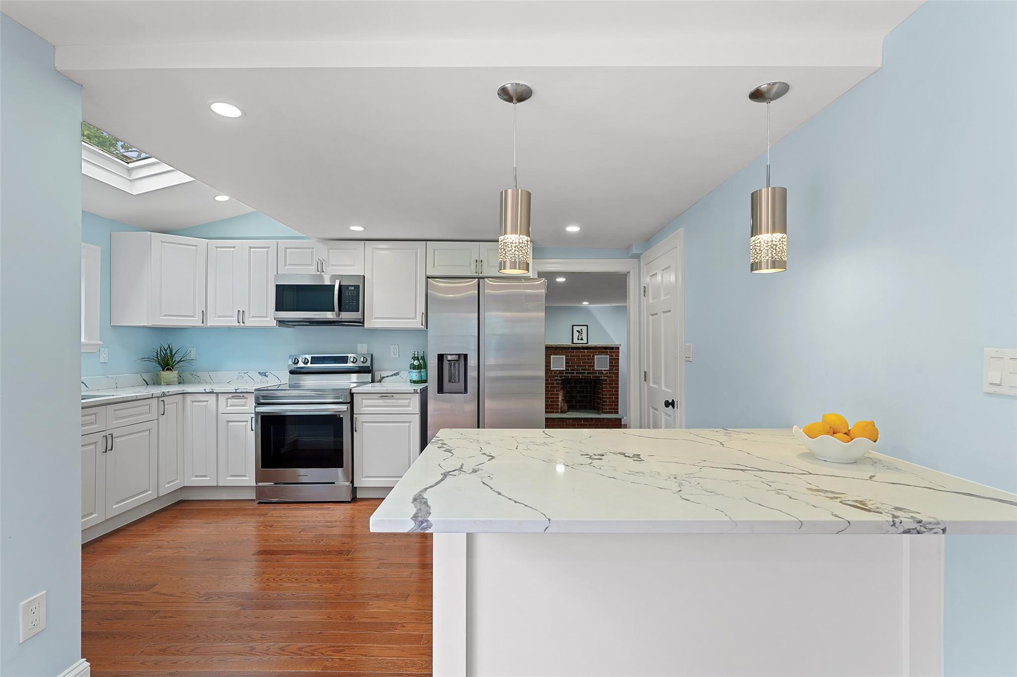 58 Whippoorwill Road East Armonk, NY 10504 - Photo 8 of 22 Kitchen with appliances with stainless steel finishes, white cabinets, wood finished floors, decorative light fixtures, and light stone countertops