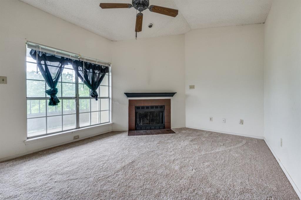 an empty room with windows and fireplace