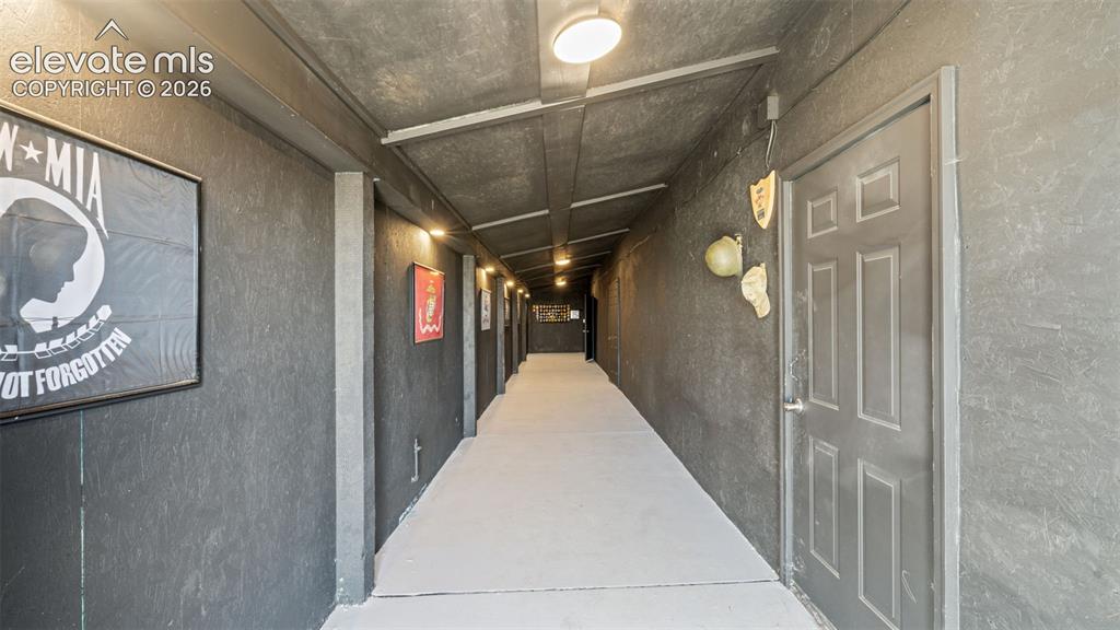 33975 Highway 94 Yoder, CO 80864 - Photo 21 of 40 Long hallway with dark textured walls, light-colored flooring, and overhead flush-mount lighting fixtures