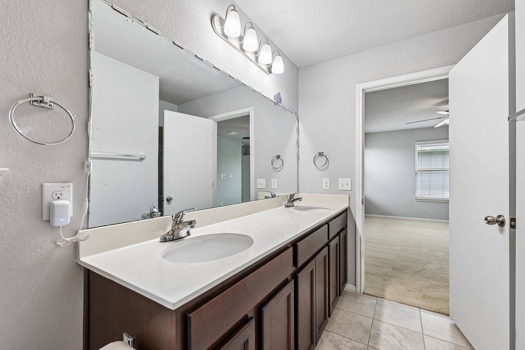 387 Guemal Road Buda, TX 78610 - Photo 33 of 39 Spacious vanity featuring a dual sink with chrome faucets and a large wall-mounted mirror