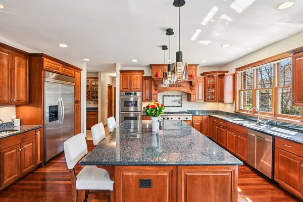 a kitchen with stainless steel appliances granite countertop a sink a stove and a wooden cabinets