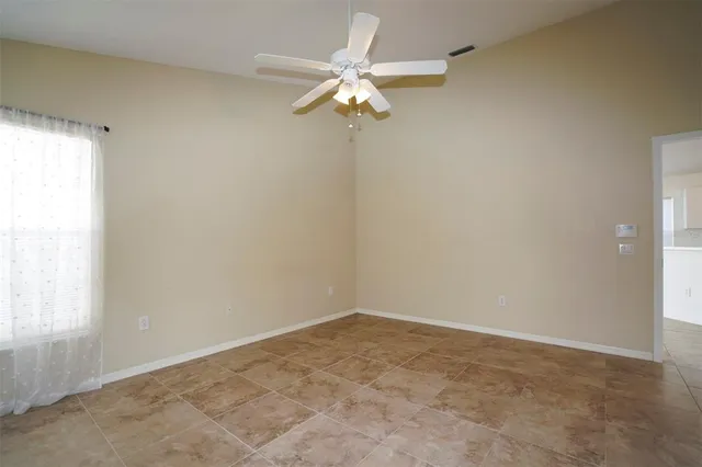 an empty room with a ceiling fan and window