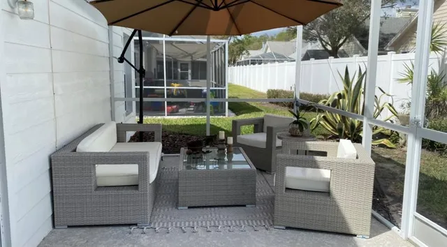 a view of a patio with couches table and chairs under an umbrella