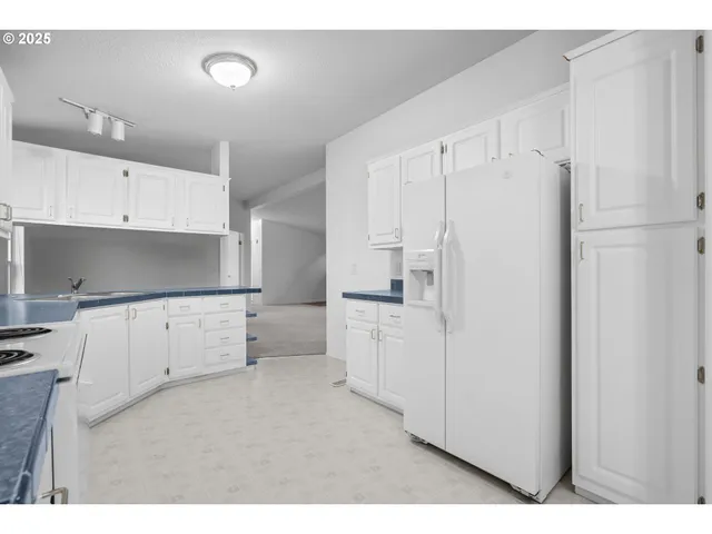 a kitchen with white cabinets and refrigerator