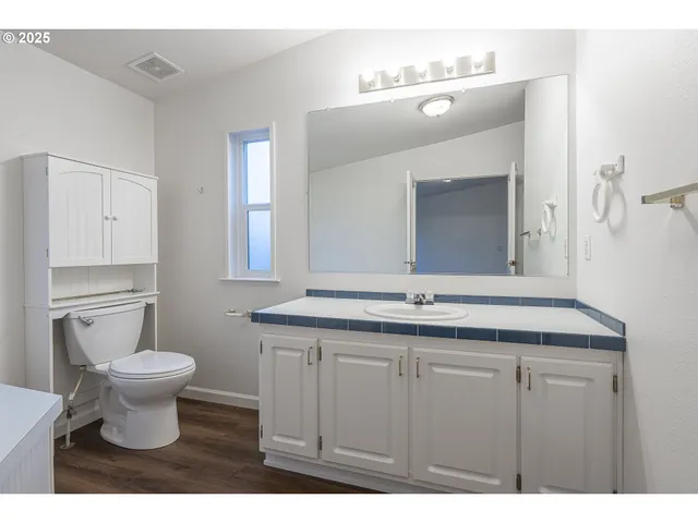 a bathroom with a granite countertop sink a toilet and a mirror