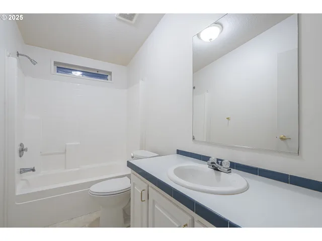 a bathroom with a granite countertop sink toilet a mirror and shower