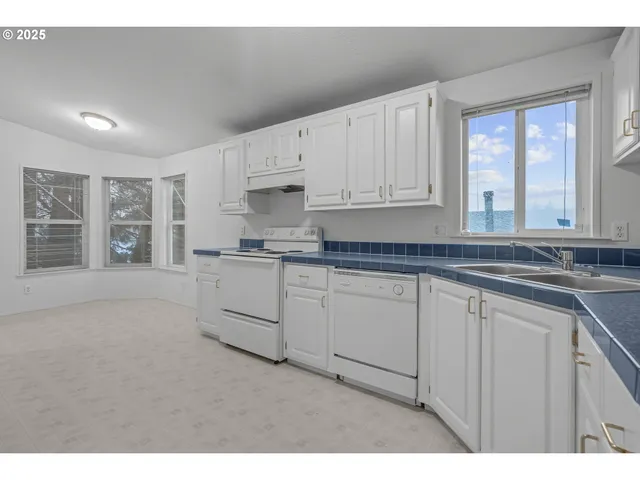 a kitchen with granite countertop white cabinets and white appliances